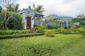 Uma casa moderna com um jardim bem cuidado, um muro de pedra e uma porta de madeira.