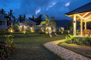 Un resort con varias villas para huéspedes, un césped bien cuidado y una zona de estar al aire libre cubierta.