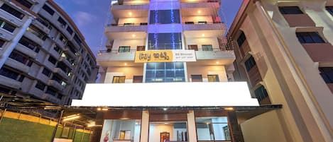 Un hotel de varios pisos con una entrada destacada, señalización y una fachada bien iluminada.