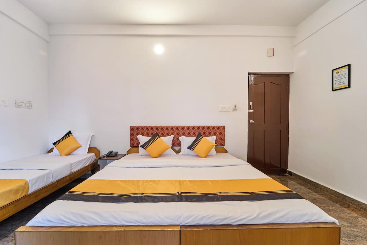 A hotel room with two single beds, a wooden headboard, a brown door, and a framed certificate on the wall.