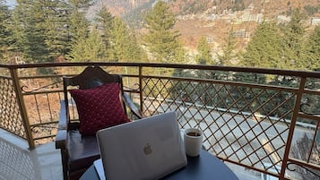 Un balcon, un ordinateur portable, une assiette de chocolats et une tasse de café.