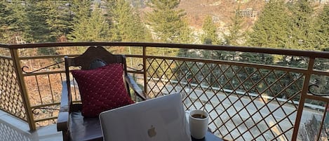 A balcony with a laptop, a plate of chocolate, and a cup of coffee.