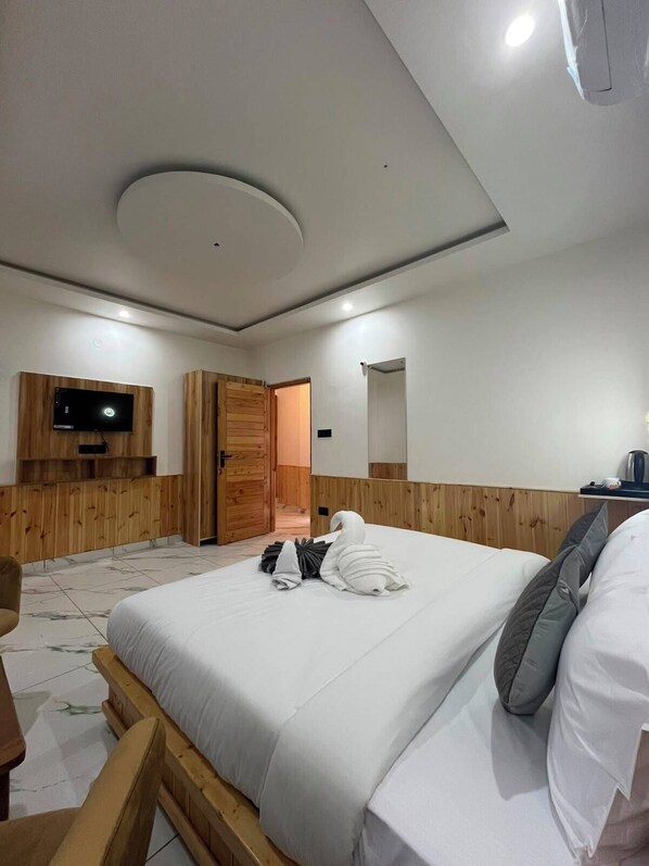 Ein Hotelzimmer mit Bett, Wandfernseher, Holztür und Spiegel.