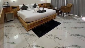 A modern hotel room with a bed, a small desk, a chair, a round ceiling light, and a window with curtains. - Hotel The Travica Kasol (Kasol)