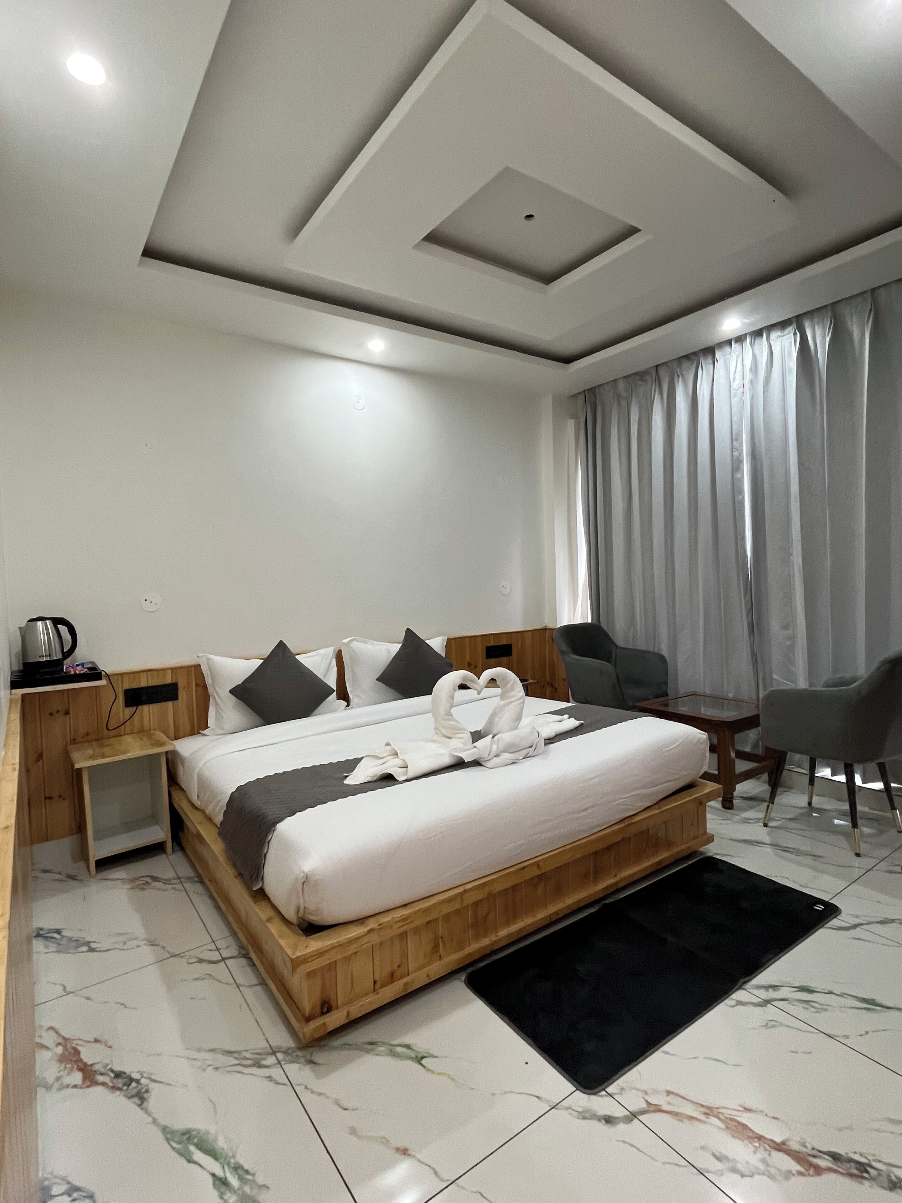 Une chambre d’hôtel moderne avec un lit en bois, une petite table de chevet, une chaise et un bureau.