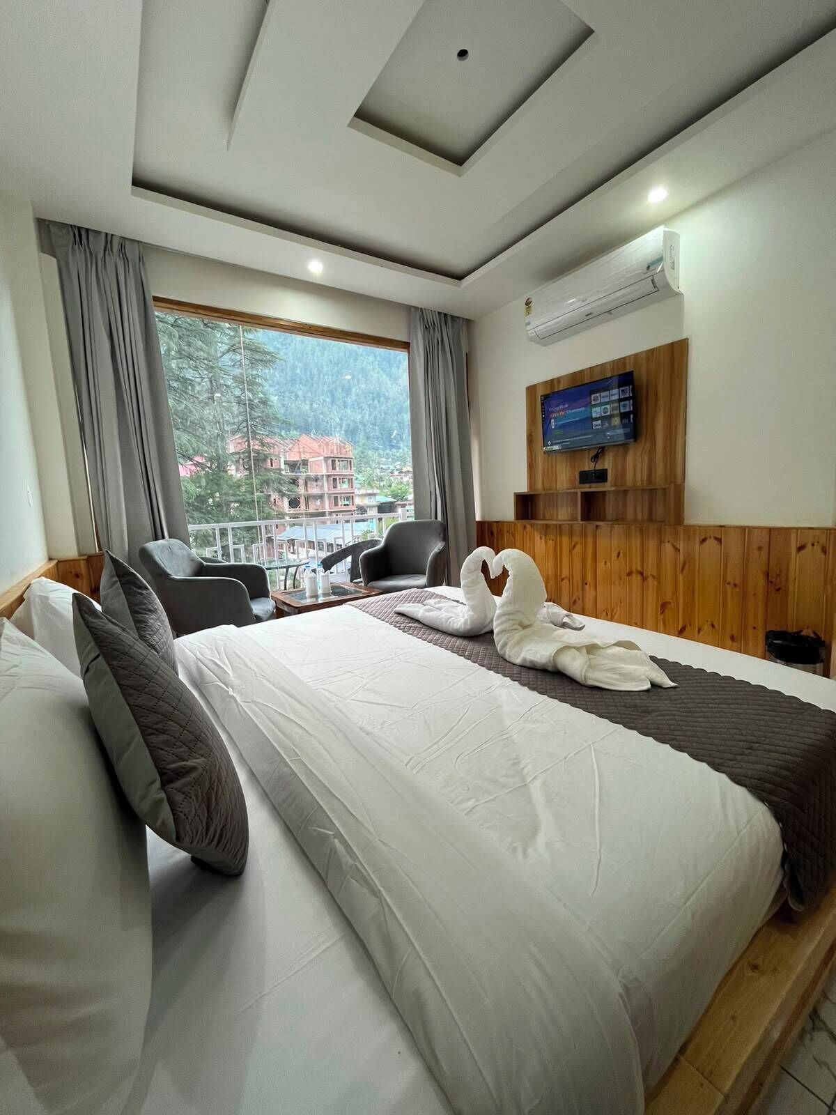 Habitación de hotel con cama, dos sillas, televisión y vistas al exterior.