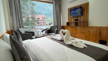 Habitación de hotel con cama, dos sillas, televisión y vistas al exterior.