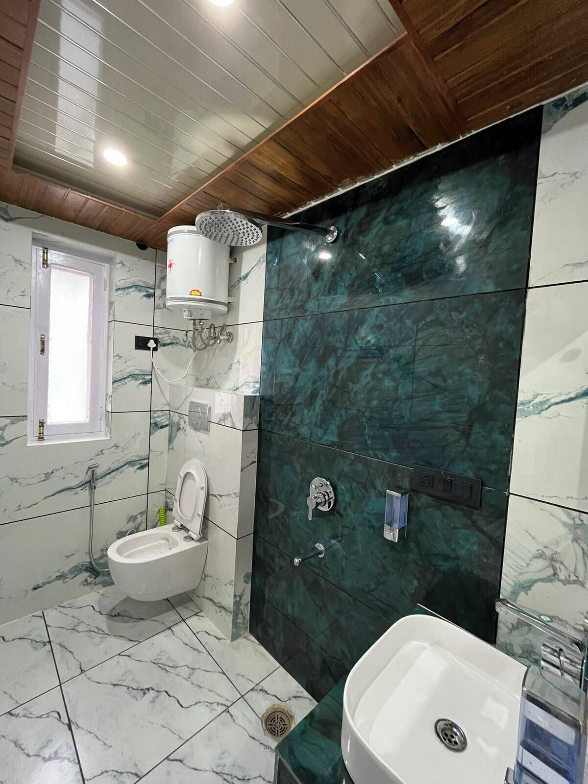 Ein Badezimmer mit Toilette, Bidet und Waschbecken, Marmorfliesen und Holzboden.