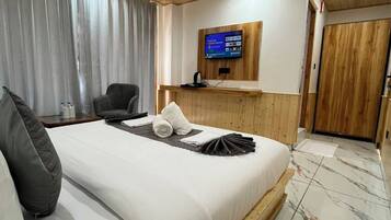 Une chambre d’hôtel avec un lit, un téléviseur fixé au mur, un plafond en bois et une porte.