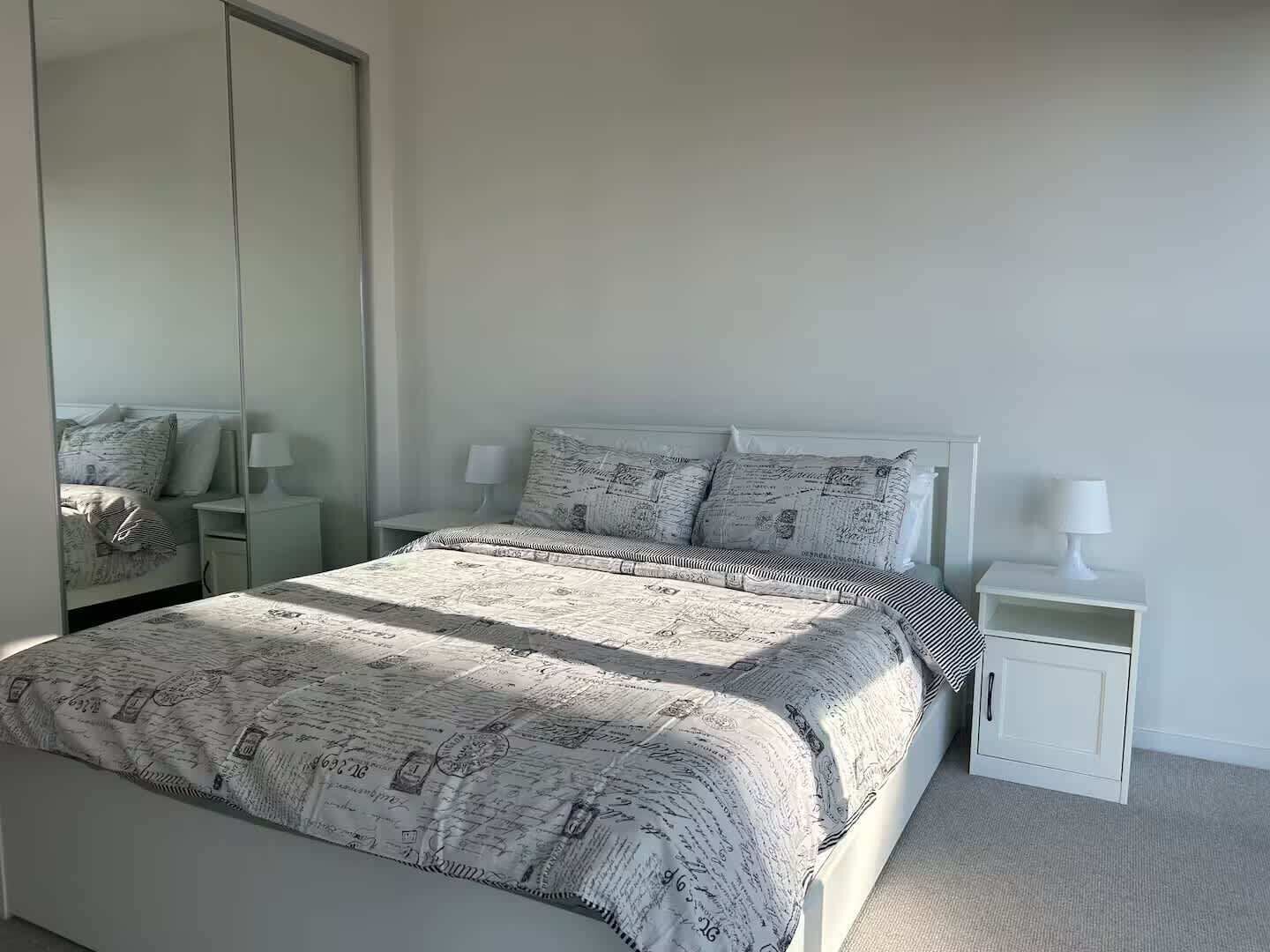A bedroom with a bed, a nightstand, a mirror, and a wardrobe.