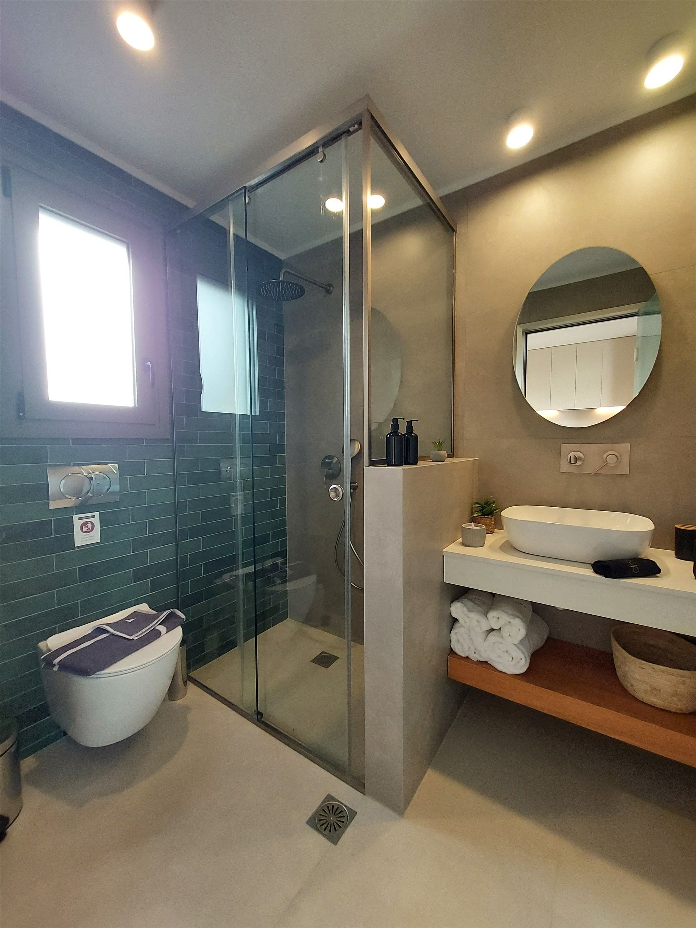 A modern bathroom with a glass-enclosed shower, a white sink, and a mirror.