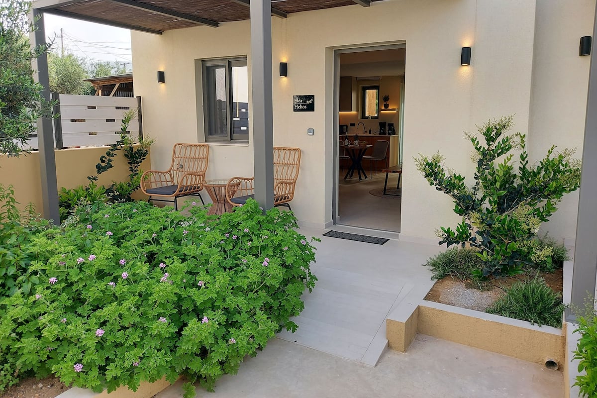 A modern house with a covered patio, outdoor seating, and a visible kitchen area.