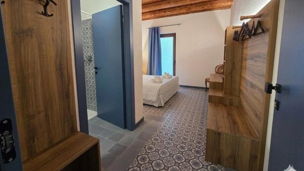 A bedroom with a bed, a wooden door, and a patterned floor.