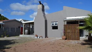 Una casa moderna amb façana gris, una xemeneia, una finestra i un portal reixa.