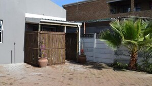 Un pati pavimentat amb una tanca de fusta, una palmera i plantes en testos.