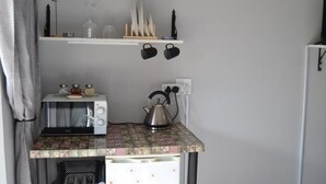 Una cuina compacta amb microones, bullidor i nevereta petita.