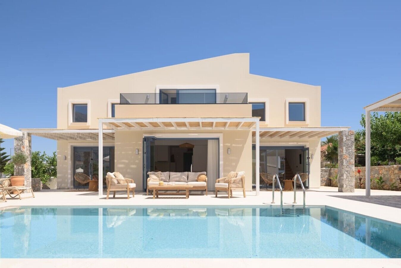 A modern two-story house with a swimming pool, outdoor seating, and a covered patio area.