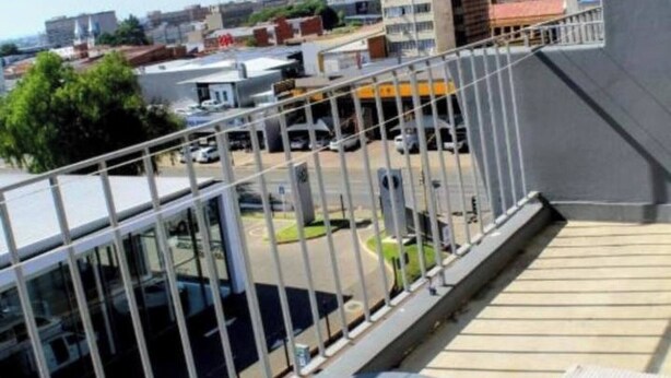 A balcony with a view of a parking lot and buildings. - Beautiful City Centred Penthouse (Bloemfontein)