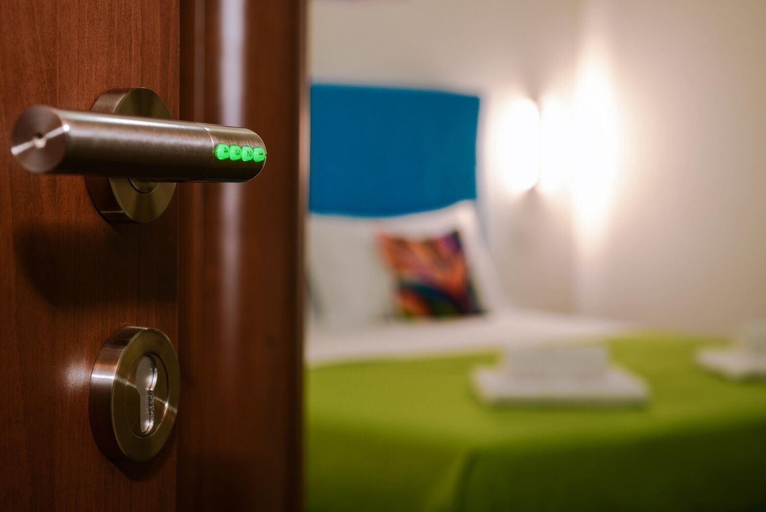 Eine Hotelzimmertür mit Kartenlesegerät und ein Bett mit grüner Bettdecke.