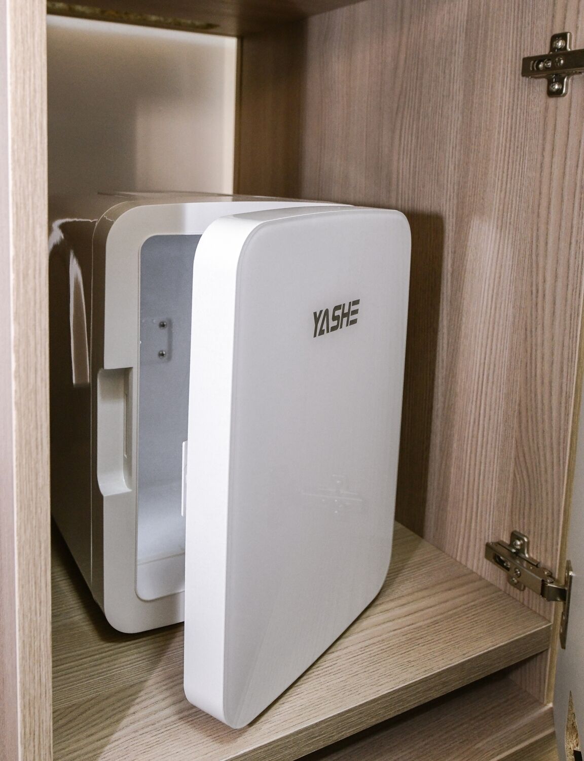 A white YASHE refrigerator in a wooden cabinet.