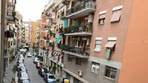 Una calle estrecha en la ciudad, flanqueada por edificios residenciales de varios pisos, coches aparcados y algunas motocicletas.