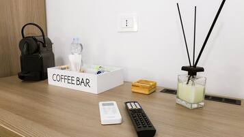 Un coin café aménagé avec une bouteille d’eau, une télécommande et une bougie parfumée sur une table en bois.