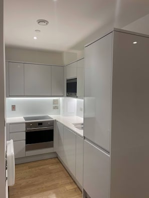 Eine moderne Küche mit weißen Schränken, einem eingebauten Backofen, einer Mikrowelle und einem Kühlschrank.