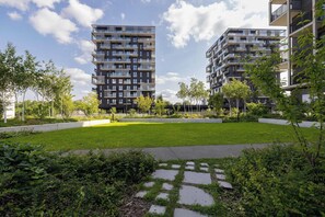Un complexe d’appartements moderne comprenant plusieurs immeubles de grande hauteur, une pelouse bien entretenue et un chemin pavé de pierres.