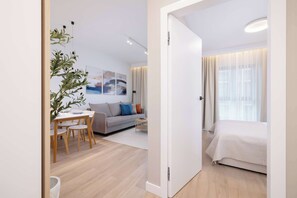 Une chambre d’hôtel moderne comprenant un lit, un canapé, une table à manger avec des chaises et une plante.