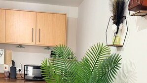 Una cocina moderna con armarios de madera, una mesa de comedor y una planta verde grande en una maceta negra.