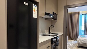 Uma cozinha compacta com geladeira preta, forno embutido e máquina de lavar louça.