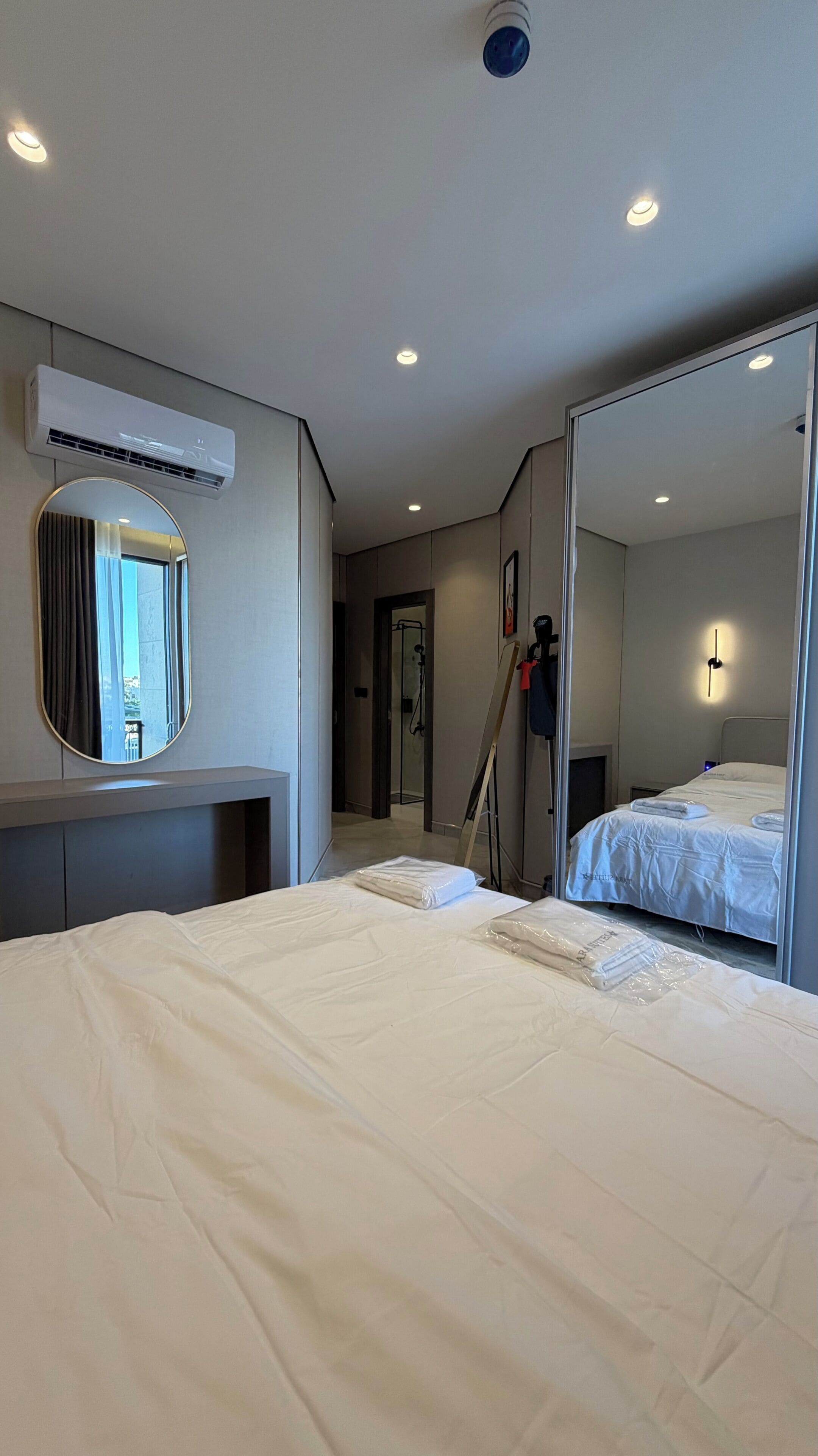 Ein Hotelzimmer mit einem Bett, einem großen Spiegel, einer Klimaanlage und einer Tür zu einem Badezimmer.