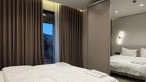 Habitación de hotel moderna con una cama grande, un espejo y vistas al exterior.