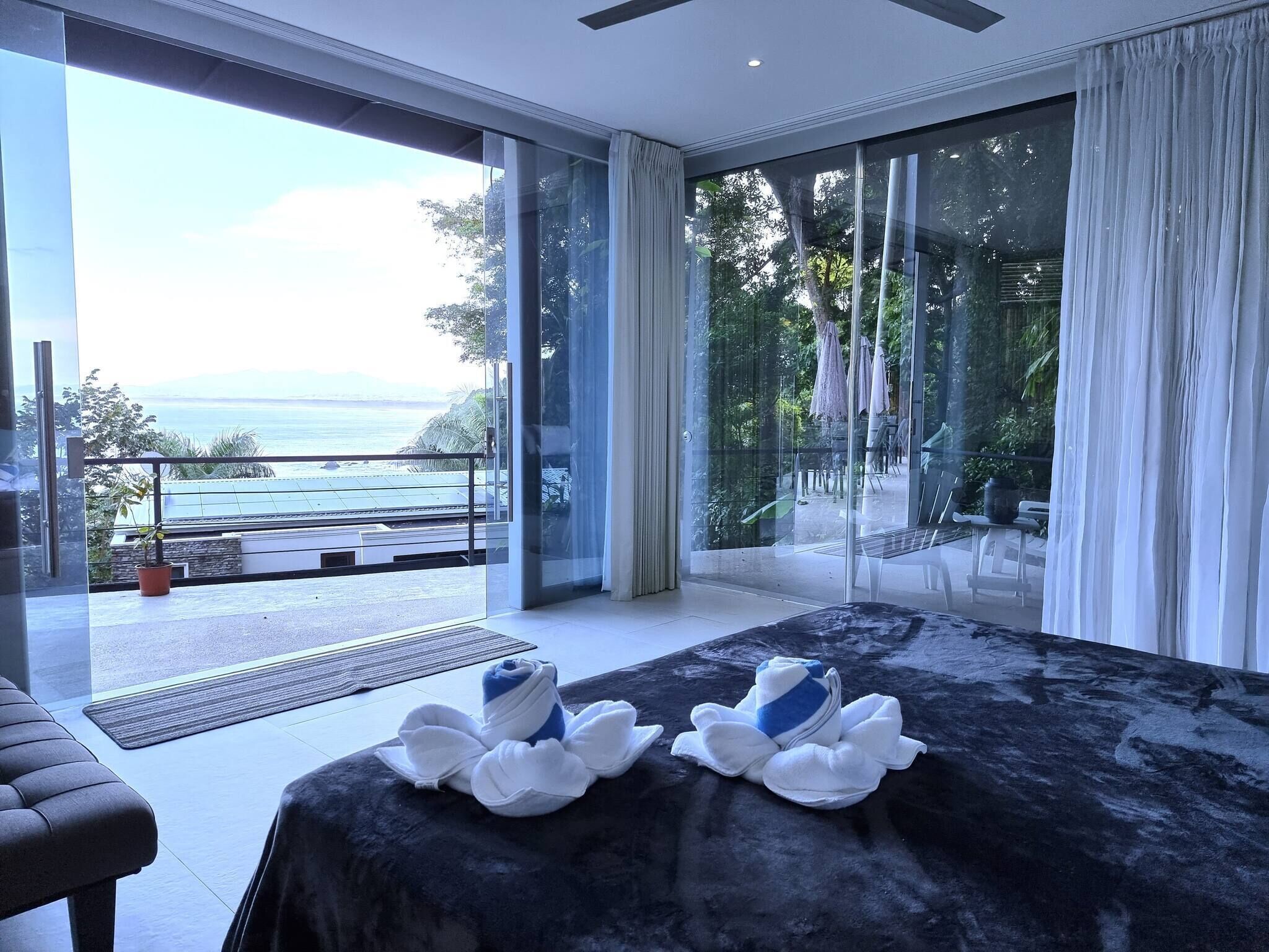 Une chambre d’hôtel moderne dotée d’un grand lit, d’un balcon avec vue sur la mer et d’une porte-fenêtre coulissante.