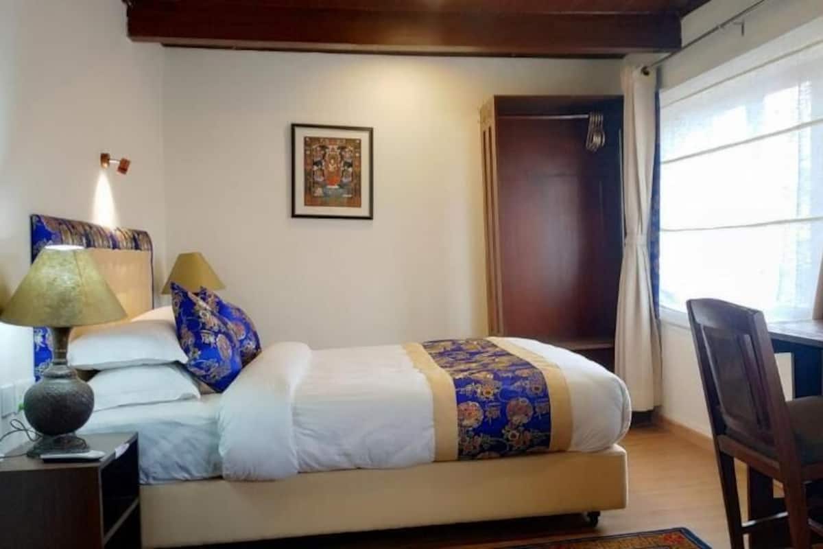Un dormitorio con cama, mesita de noche, lámpara, silla y armario.