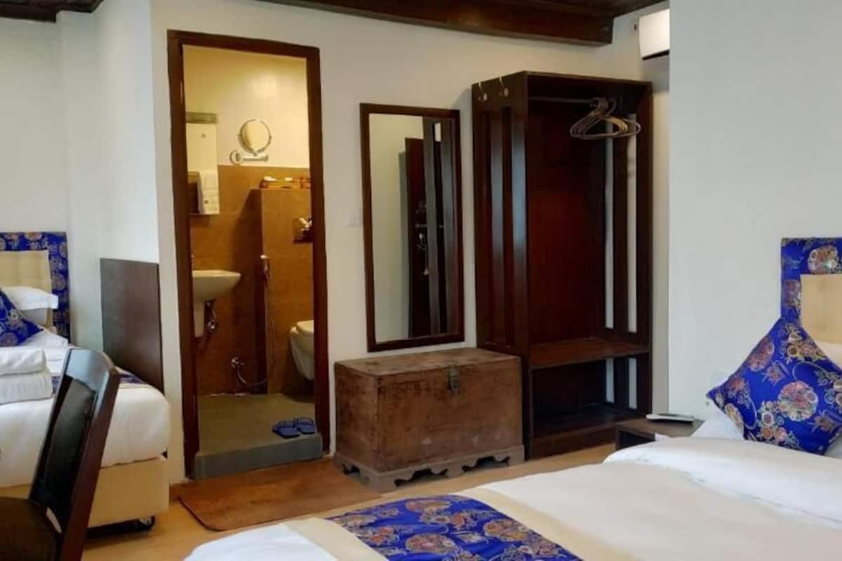 Una habitación de hotel con una cama, un cofre de madera, un espejo y un armario.