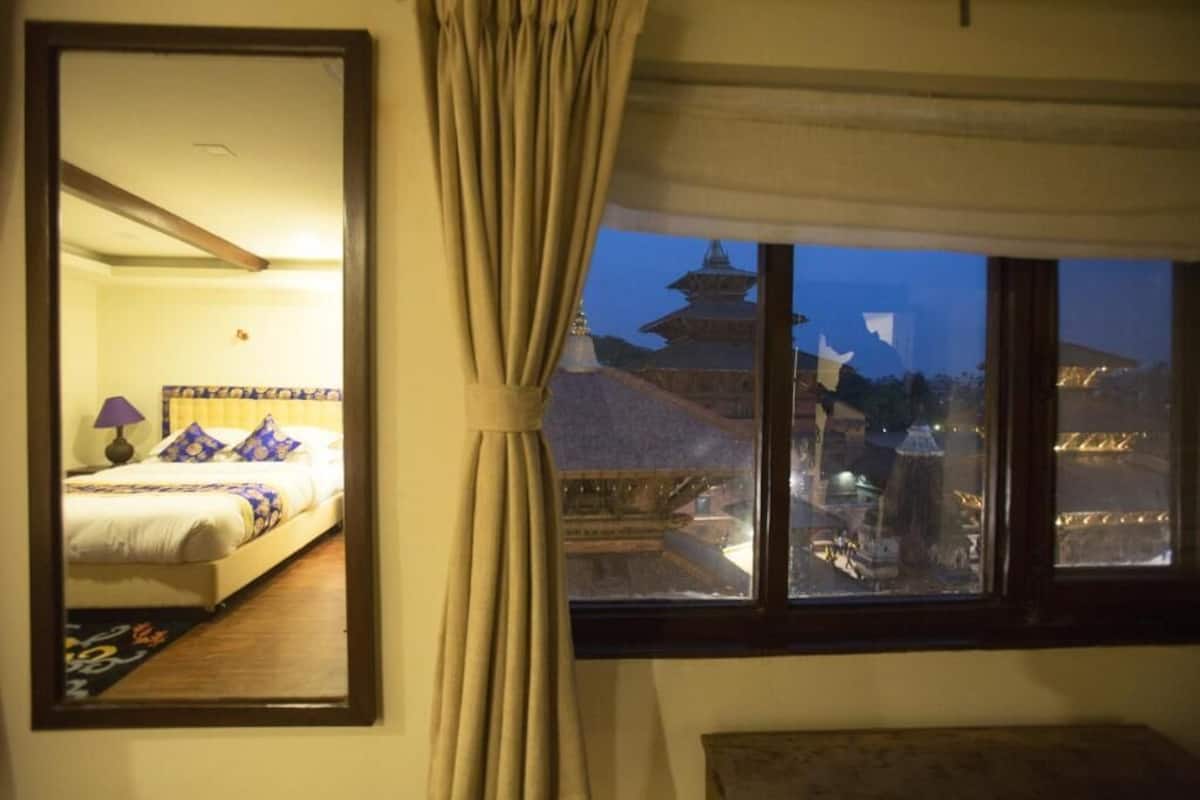 Habitación de hotel con cama, mesita de noche, lámpara y vista a una pagoda por la ventana.