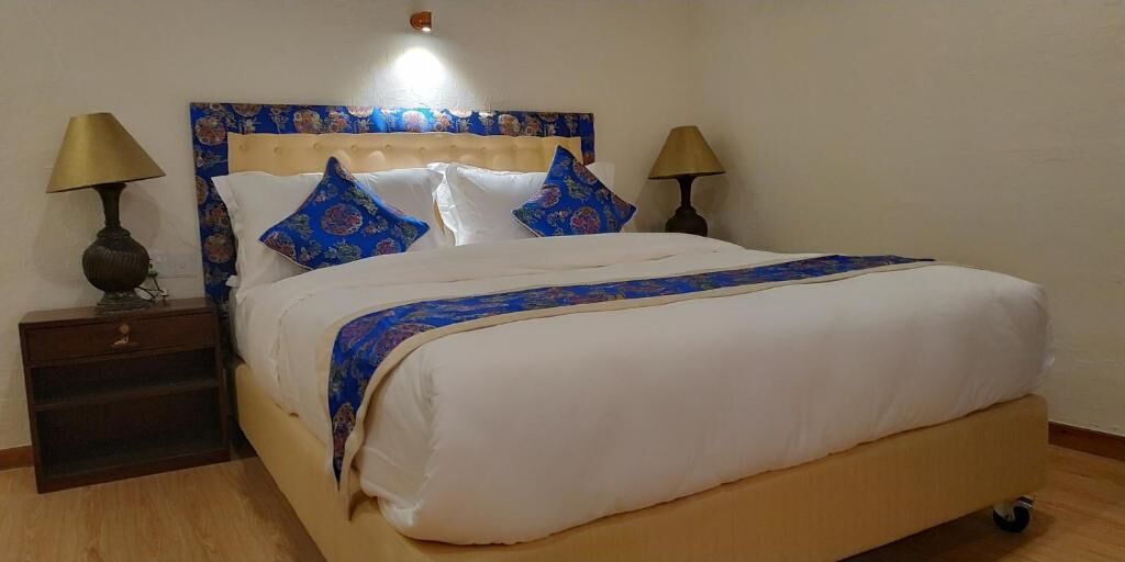 Una cama con cabecera, dos mesitas de noche y dos lámparas.