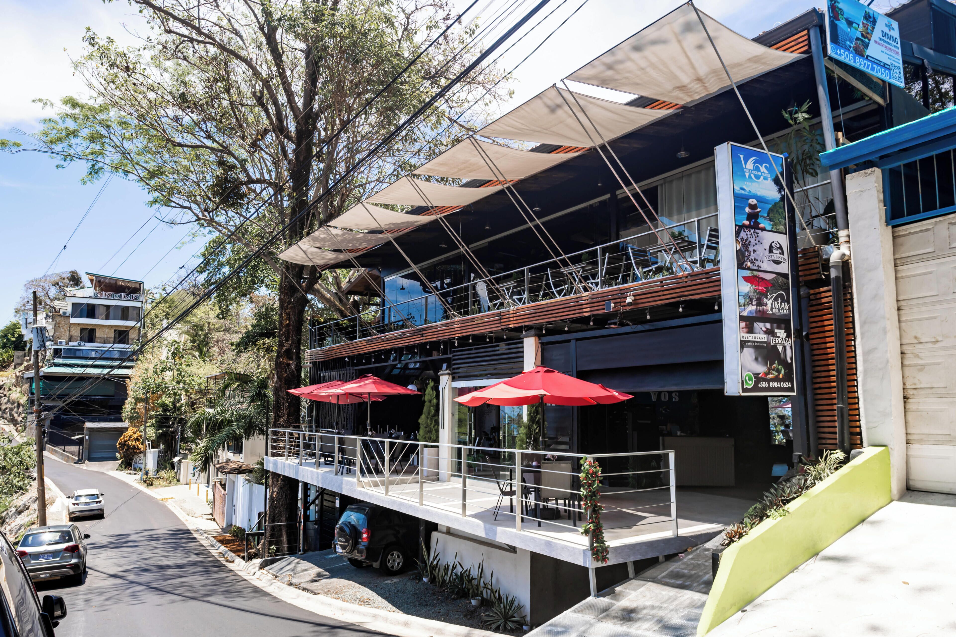 A restaurant with outdoor seating, a covered area, and a visible signboard.