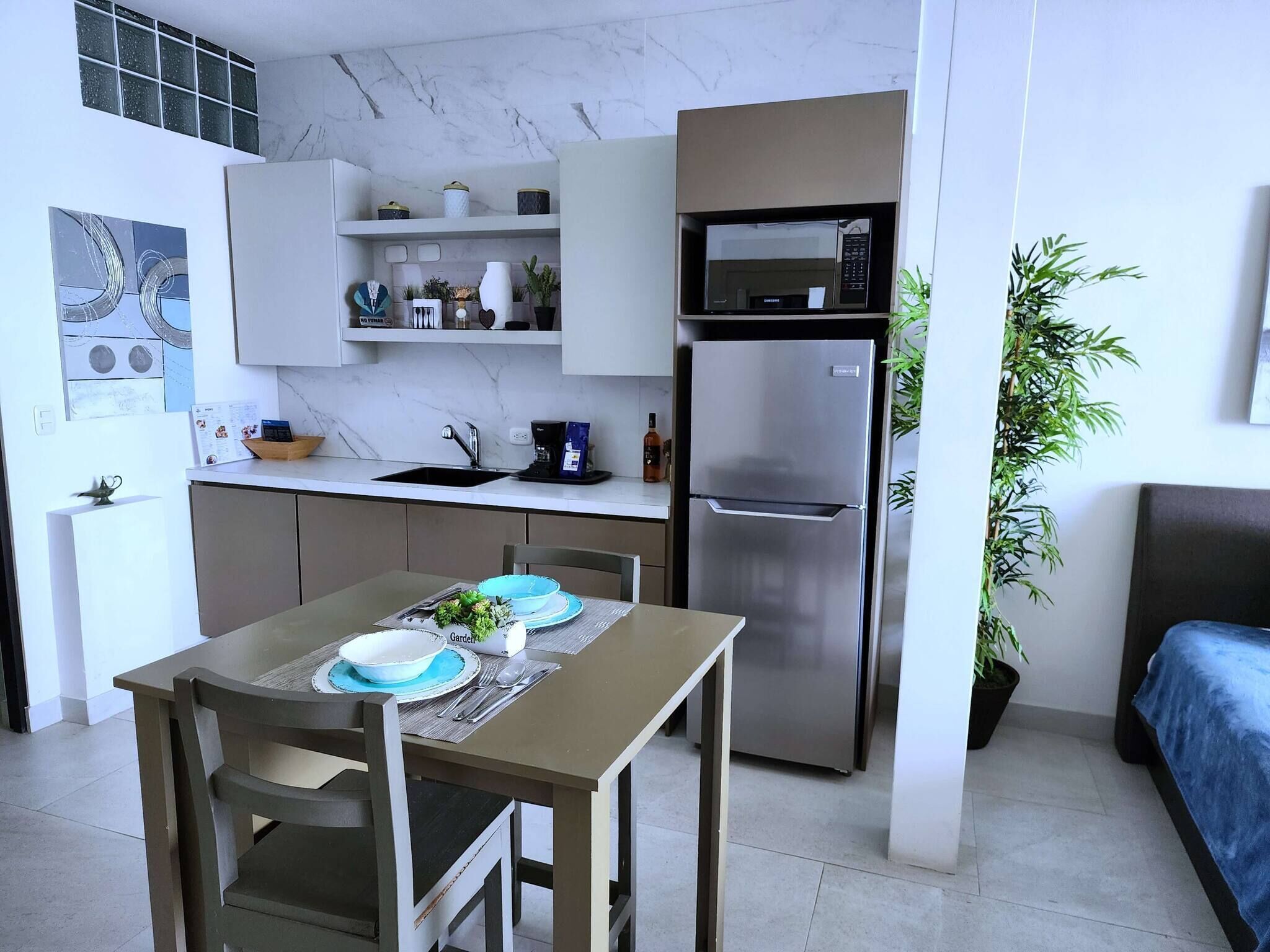 A compact kitchen with a refrigerator, microwave, and a dining area with a table set for two.