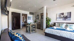 Ein modernes Hotelzimmer mit Bett, einer Sitzecke, einem Essbereich und einer Küche.