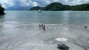 A beach with a sandy shore, a few people, and a boat in the water.