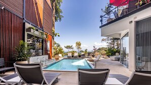 A pool area with lounge chairs, a hot tub, and potted plants.