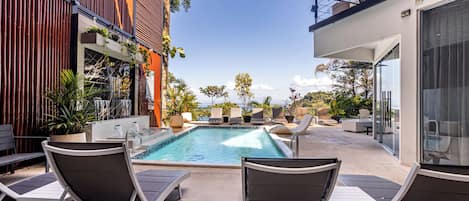 A pool area with lounge chairs, a hot tub, and potted plants.