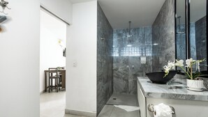 Un baño moderno con ducha, un lavabo con encimera de mármol y un espejo.