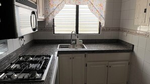 A kitchen with a gas stove, a sink, and cabinets. - The Distrito Atelier (Santo Domingo)