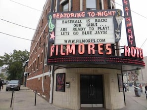 A theater marquee with 'FILMORES HOTEL' and a sign promoting a baseball event.