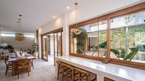 Een moderne keuken met een groot schiereiland, houten barstoelen en uitzicht op het groen.