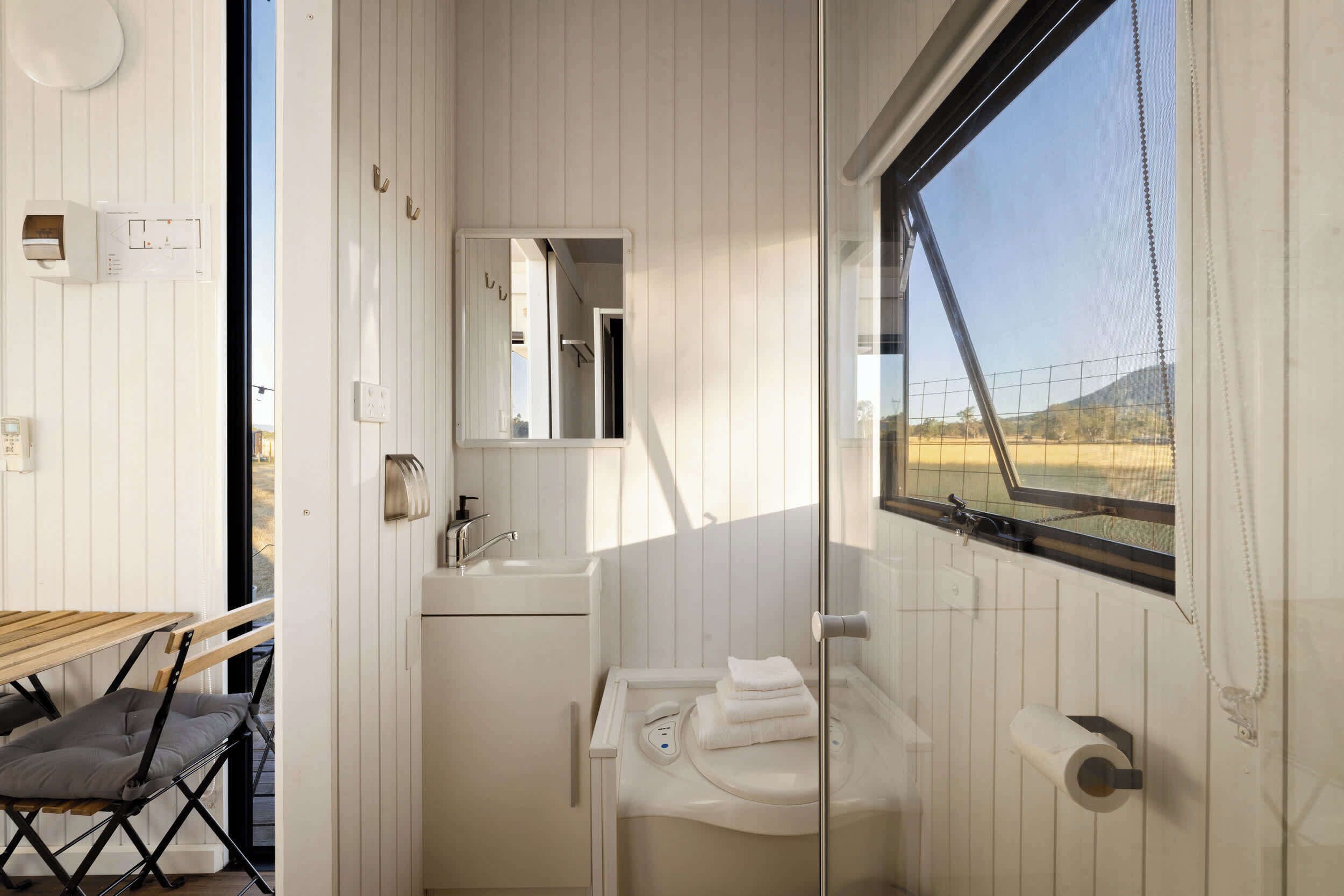 Ein kleines Badezimmer mit Waschbecken, Spiegel und Fenster.