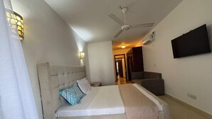 A bedroom with a bed, a chair, a television, and a ceiling fan. - Charming 2-bedroom apartment with AC in Mombasa (Mombasa)